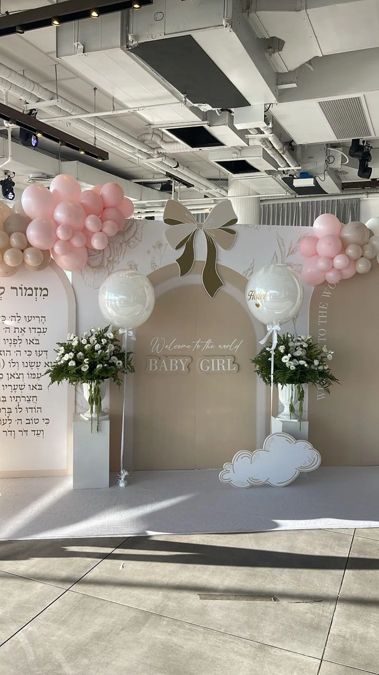 בלונים ורודים ולבנים לצד סידורי פרחים